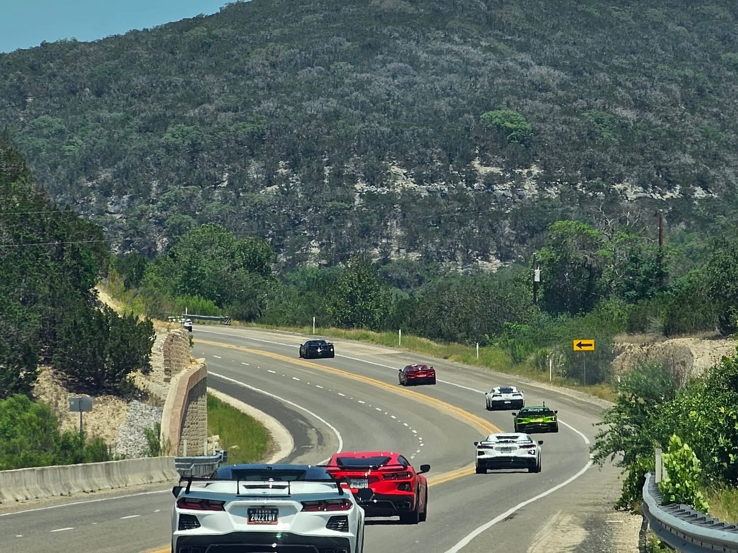 A convoy of Corvettes driving together on a scenic Texas road